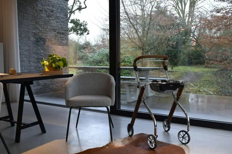 Care home lounge with a walking frame beside a window chair